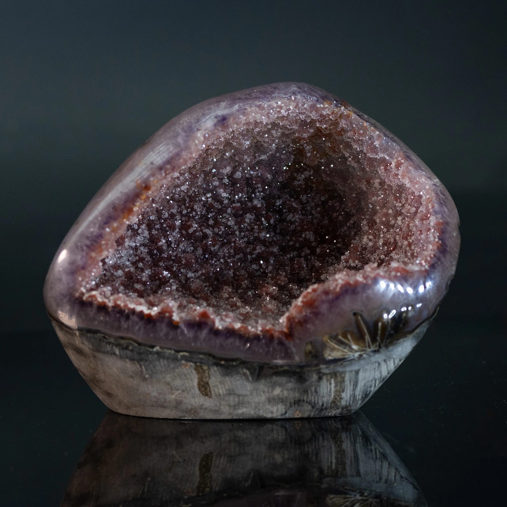 Geoda de amatista ancha y baja, abierta de frente, sobre fondo negro con reflejo