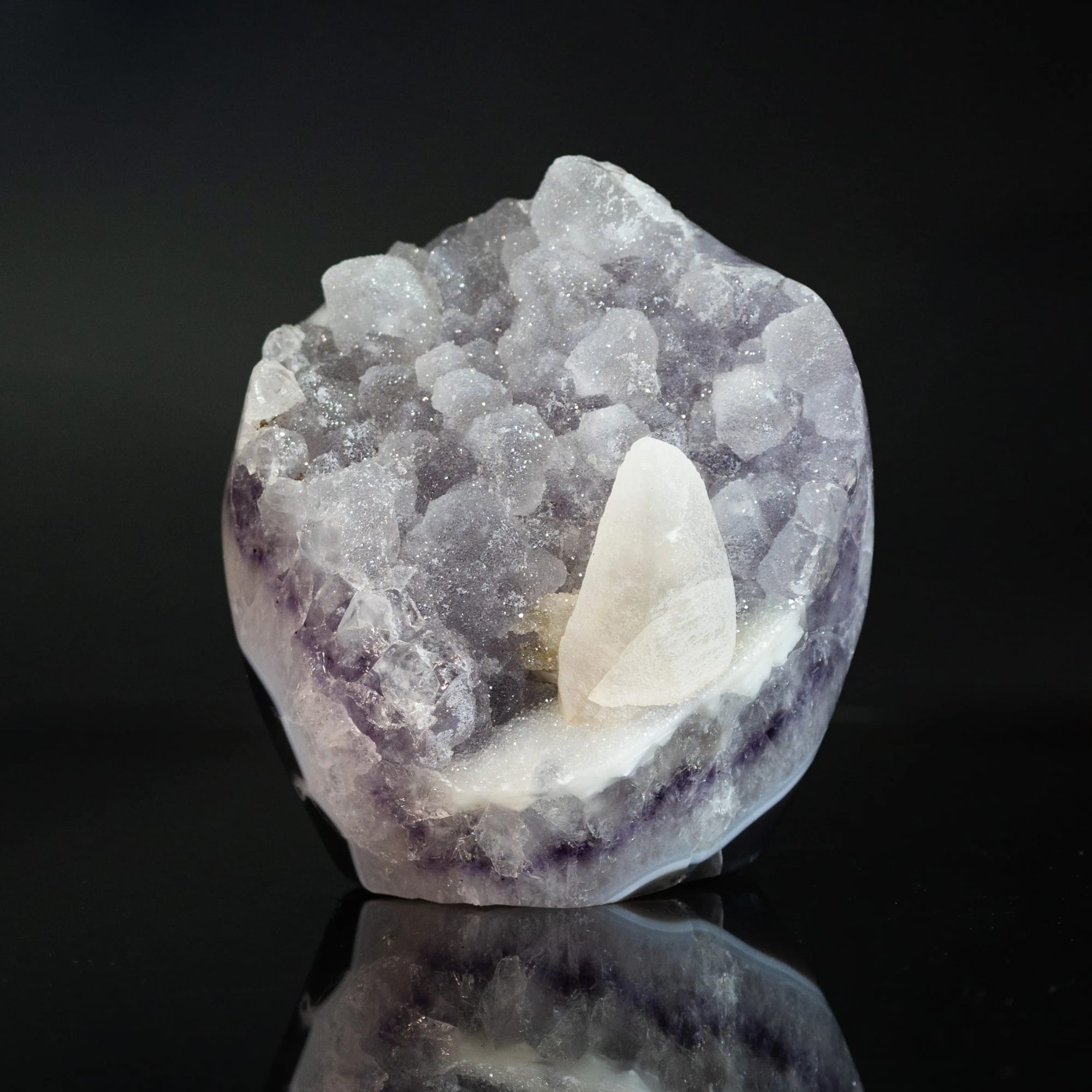 Geoda de cuarzo claro con un cristal de calcita blanco en el centro, sobre fondo negro