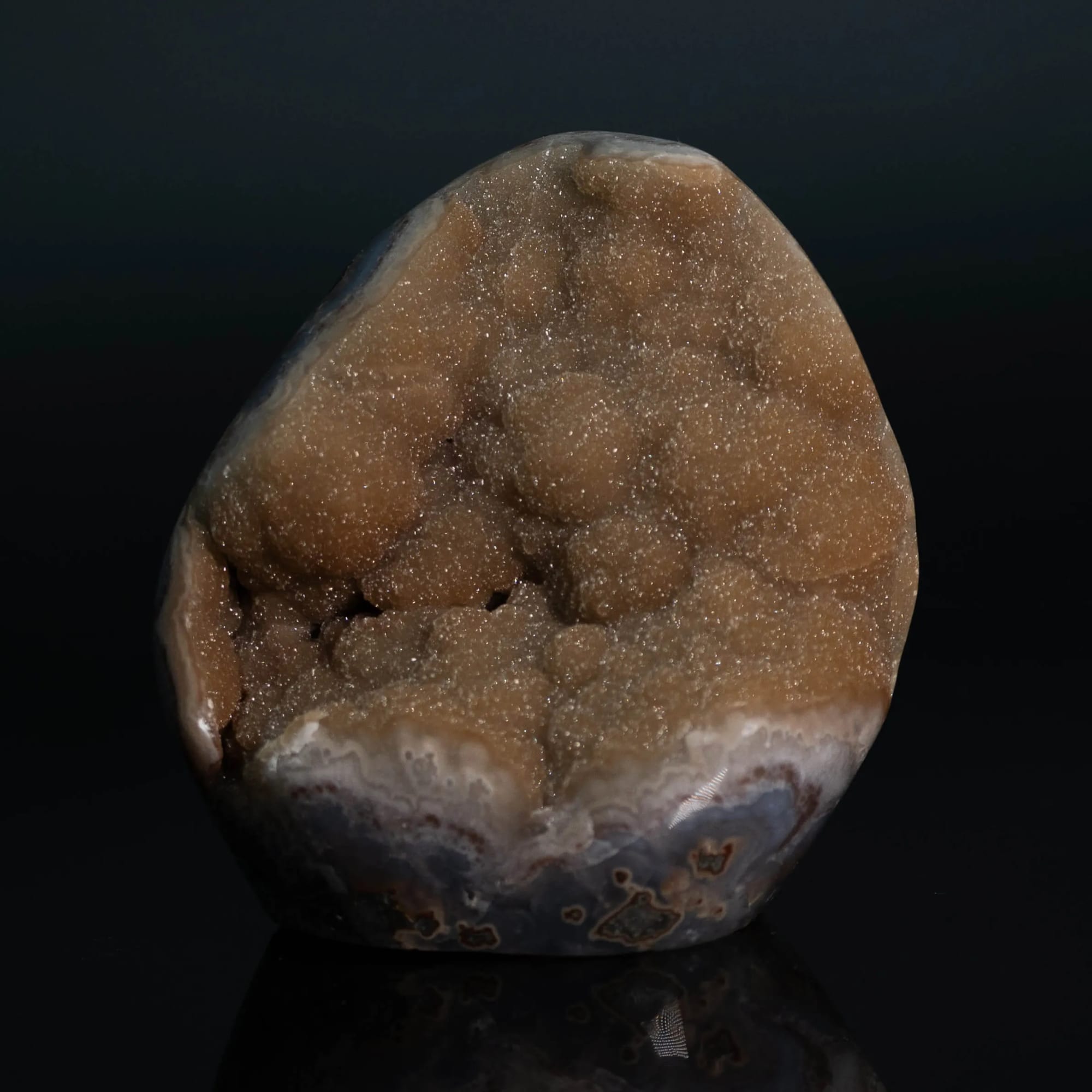Geoda de drusa dorada sobre cuerpo de ágata, sobre fondo negro con reflejo